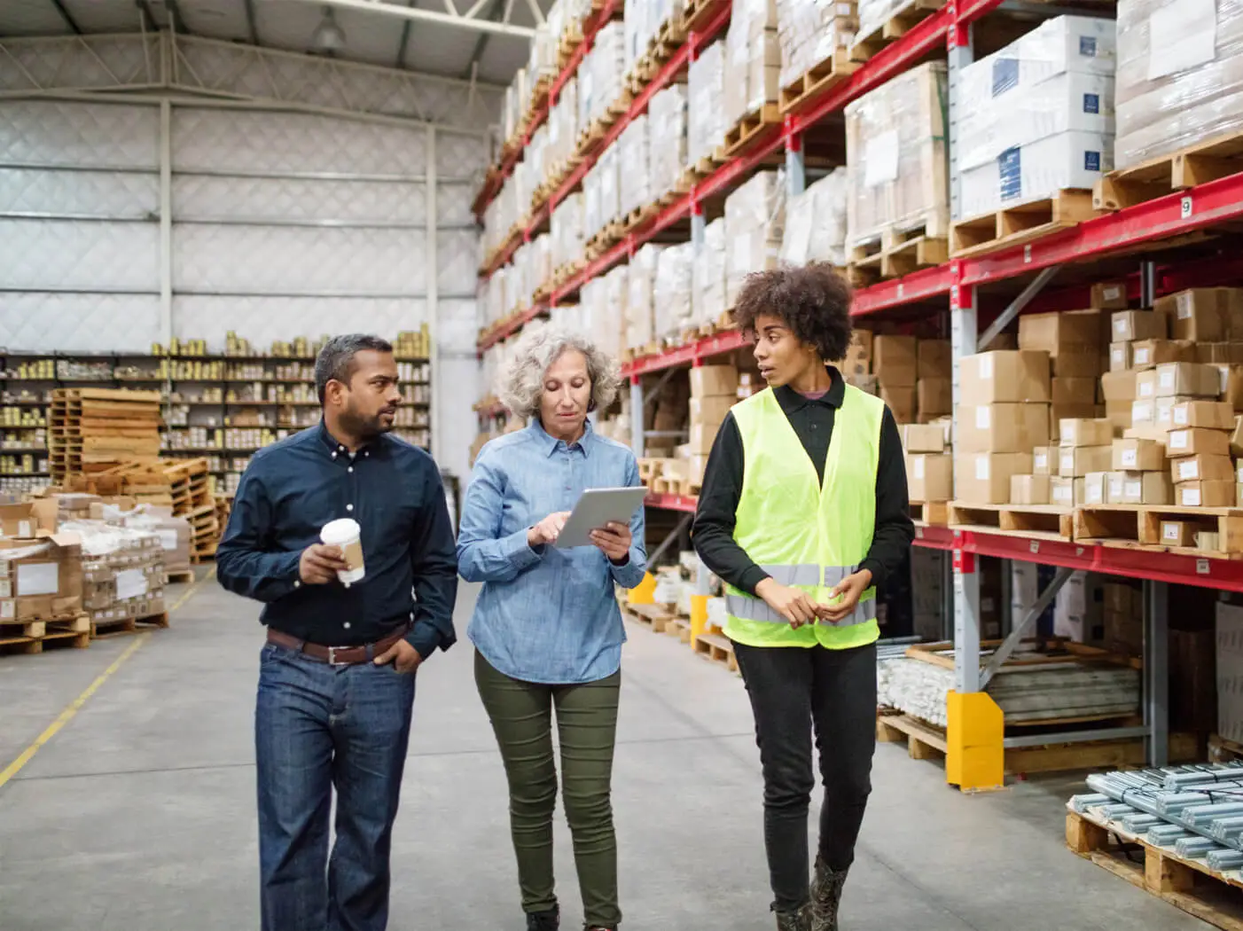 Three people in a warehouse walk while in discussion