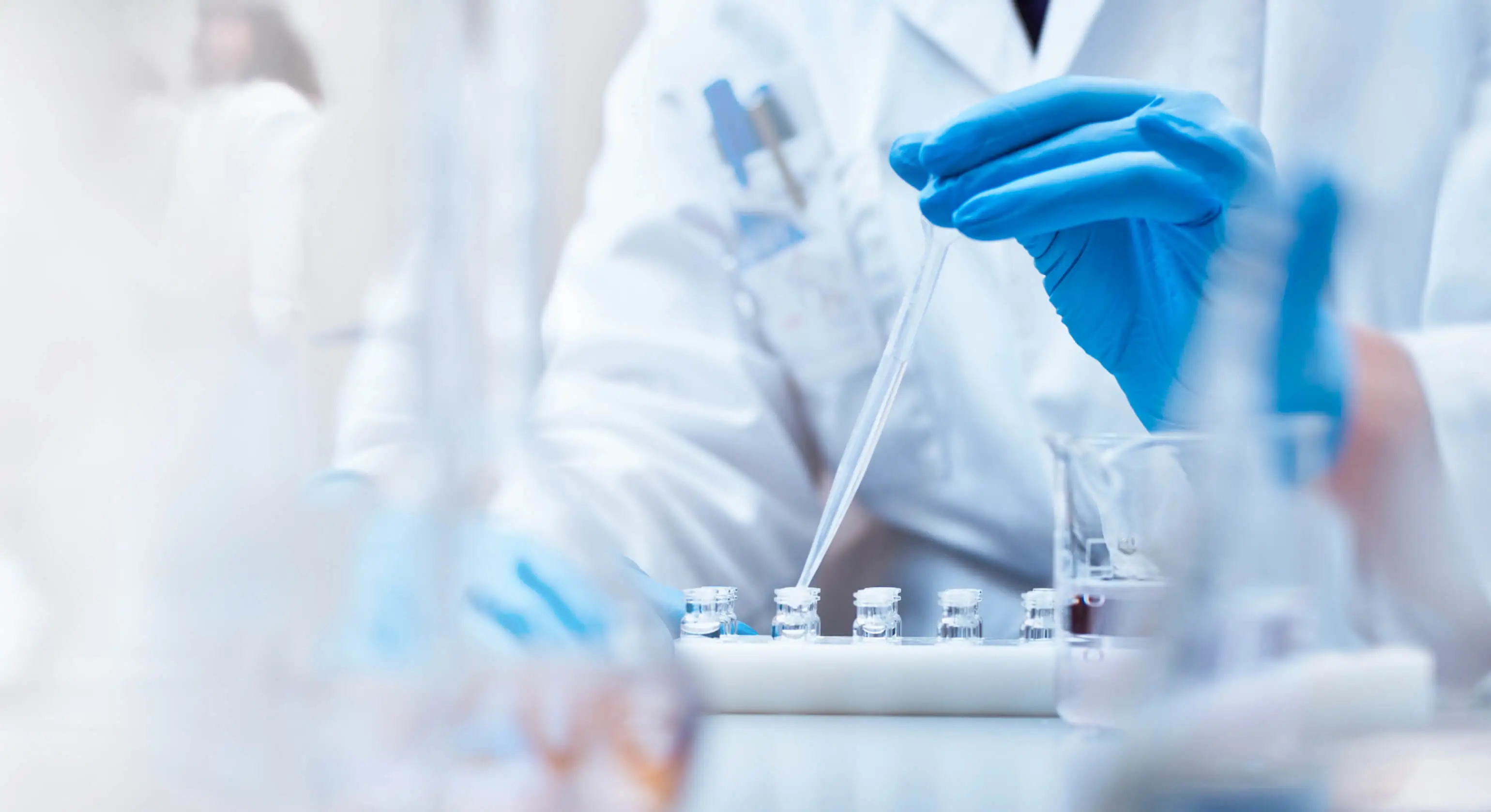 A technician squeezes the contents of a syringe into vials.