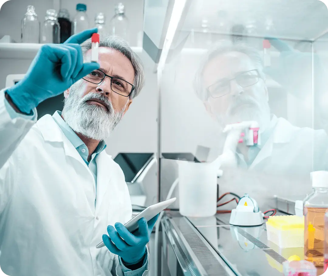 A scientist studies a vial that he's holding between his fingers.