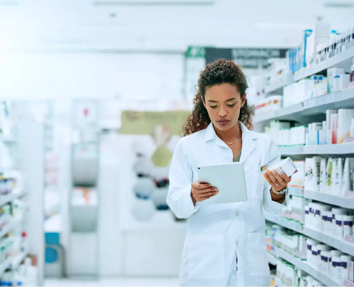 A pharmacist looks at a tablet while searching for a medication