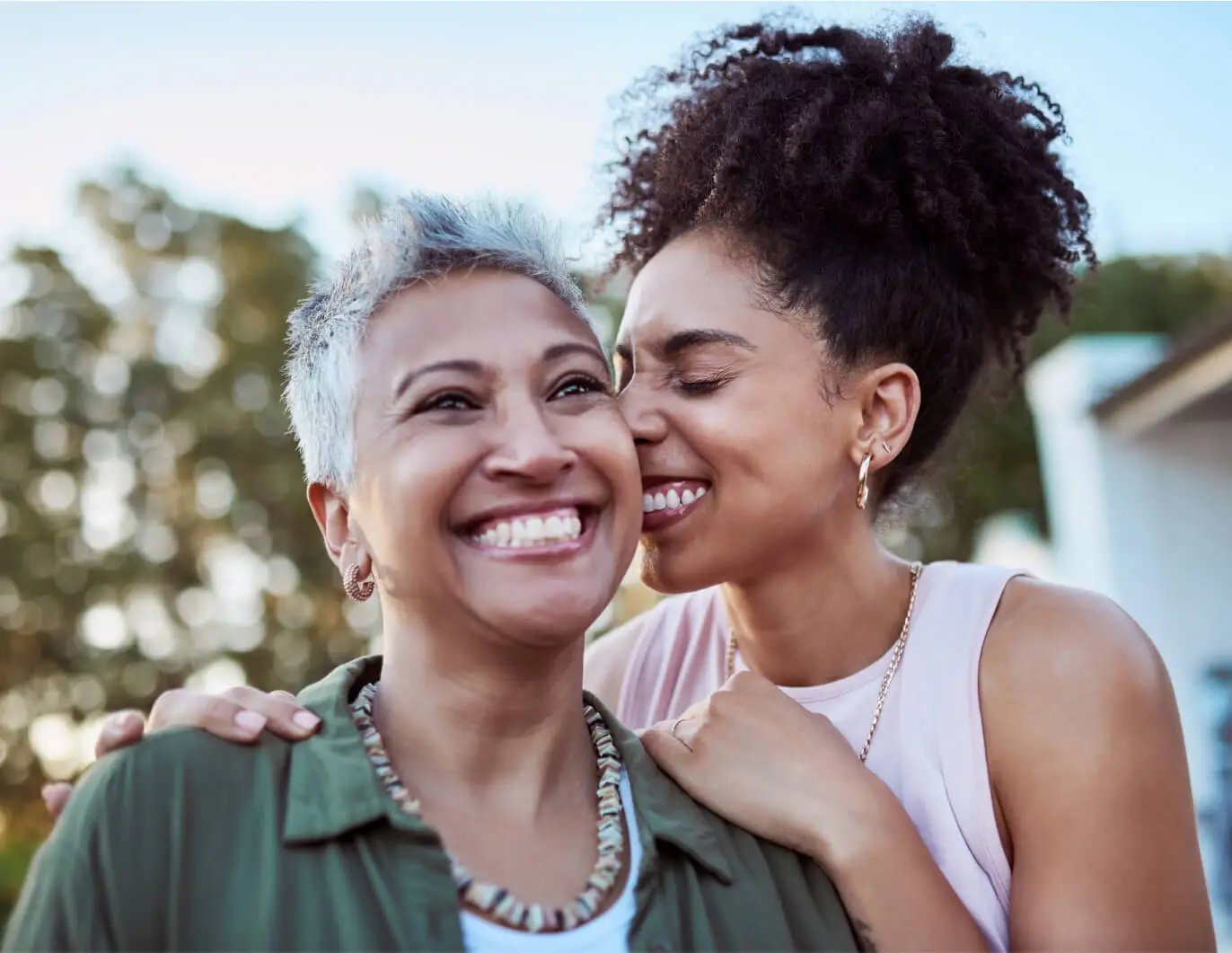 A mother and adult daughter smile and embrace.