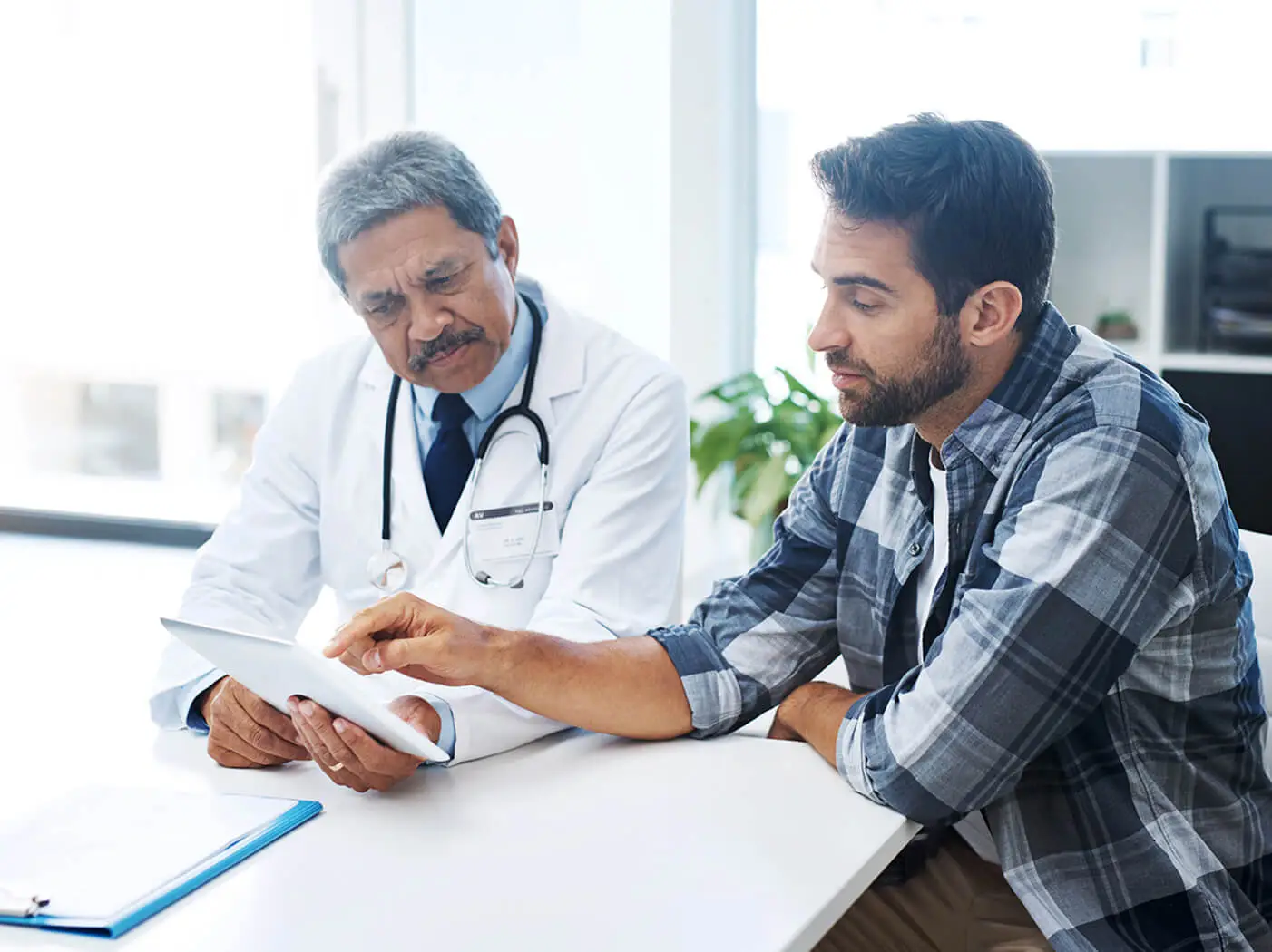 A doctor looks a tablet with a patient.
