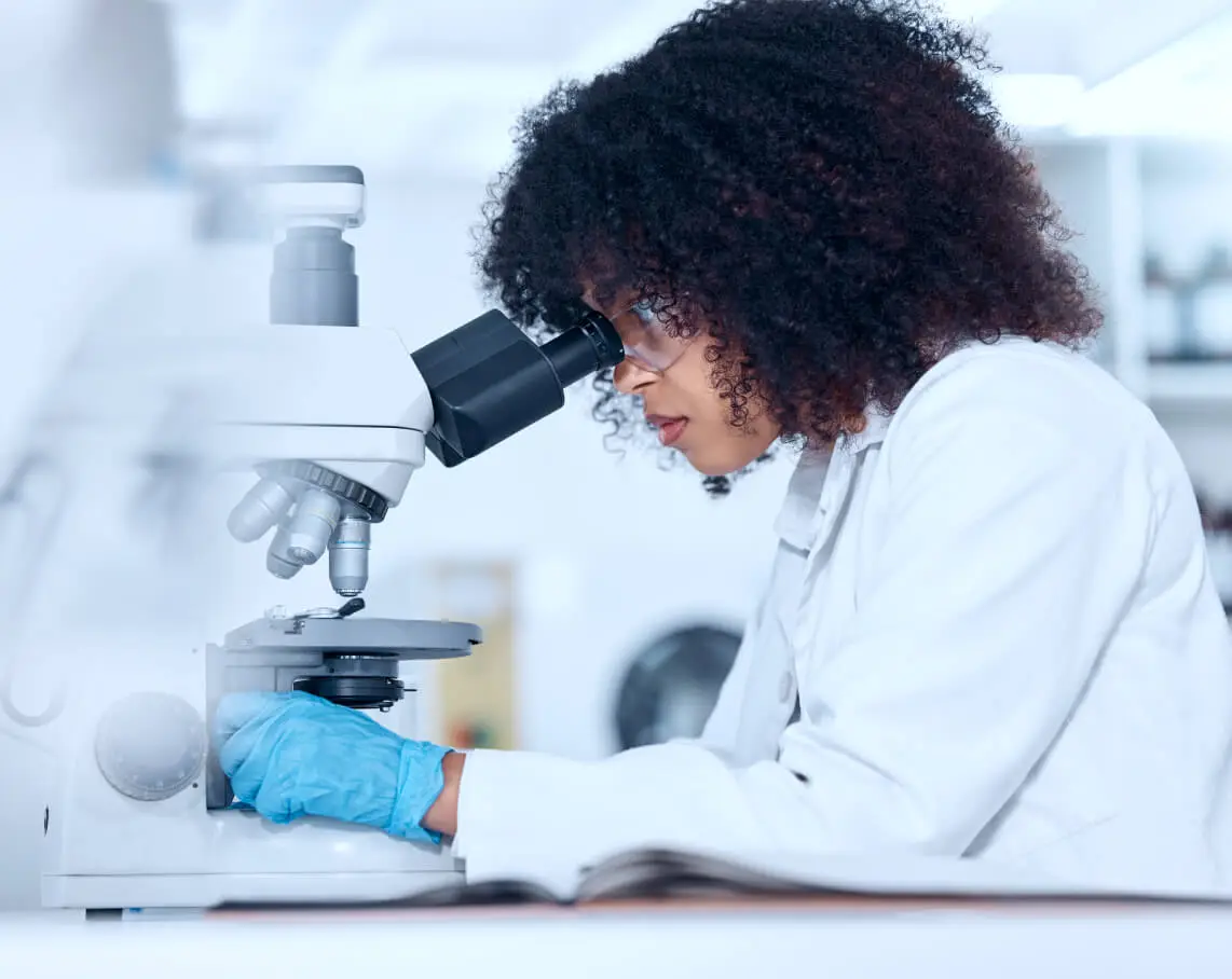 A scientist looks through a microscope