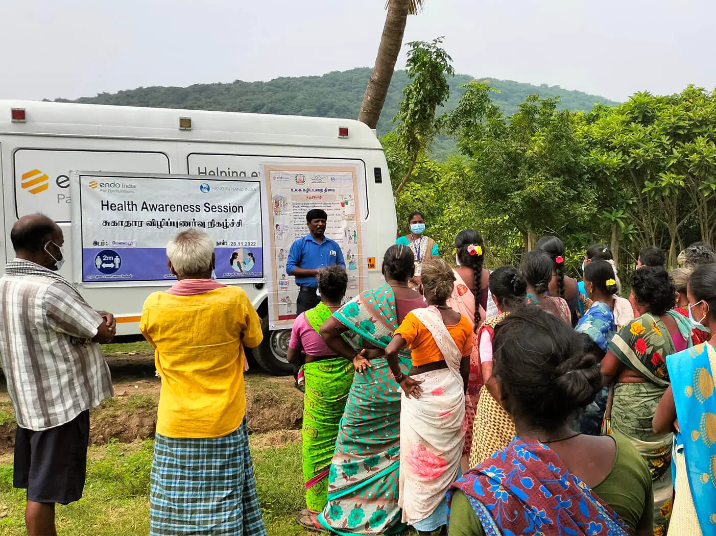 A group of patients in India gather outside a mobile health van.