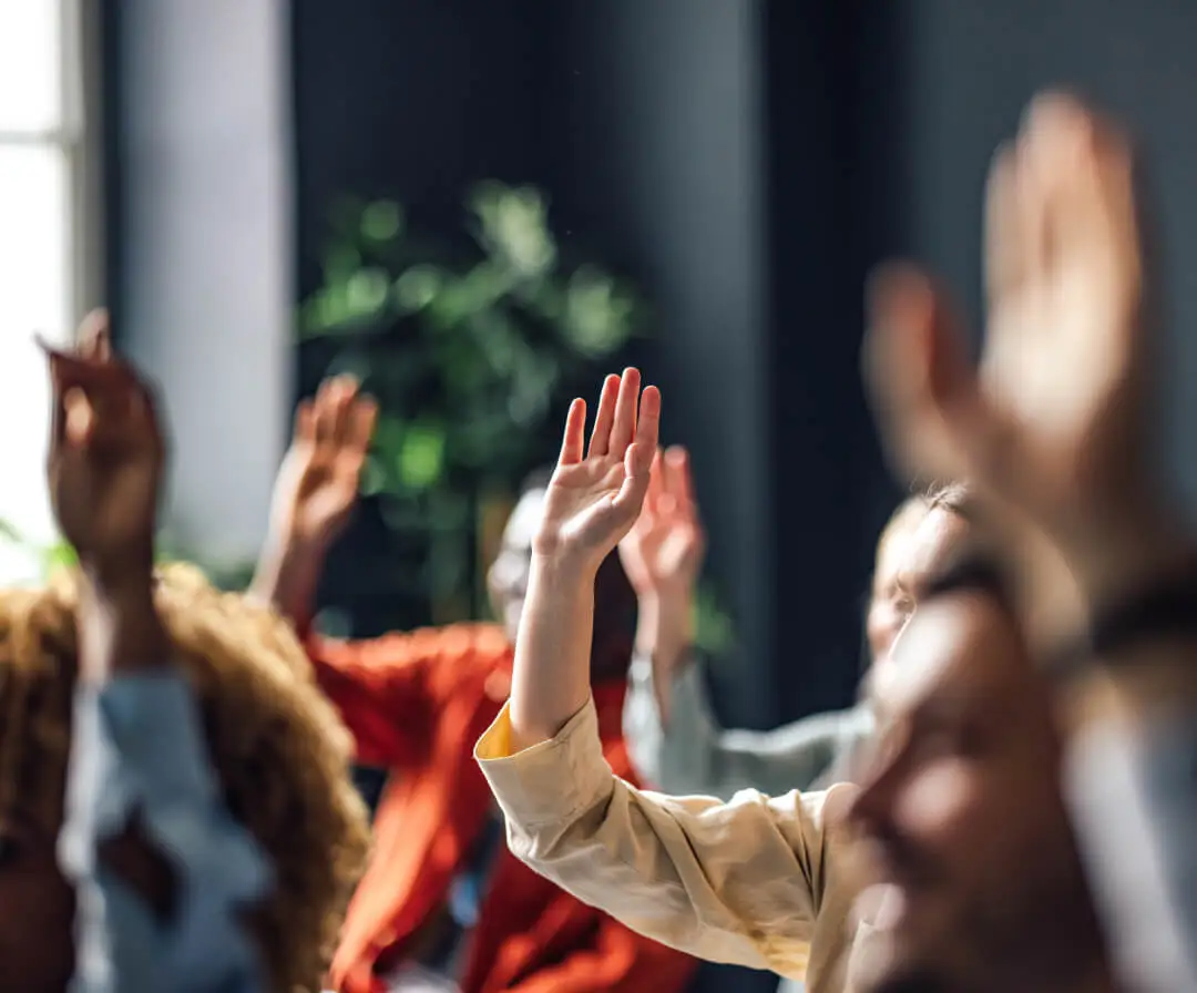 A cluster of people raise their hands in the air