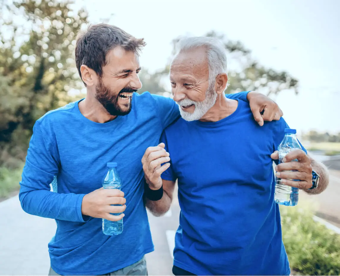 A father and son walk outside holding bottles of water