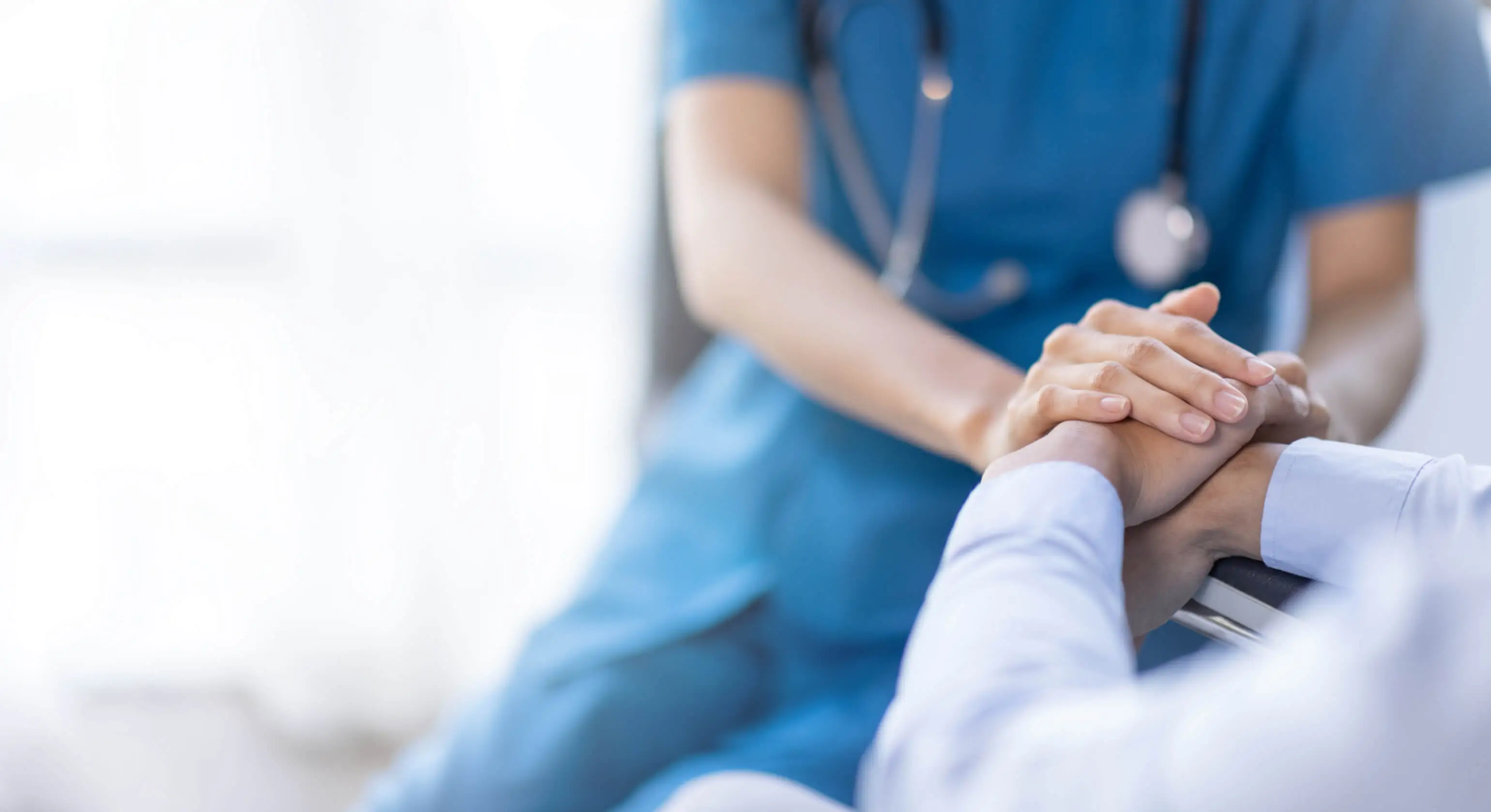 A closeup of a doctor holding the hands of a patient.