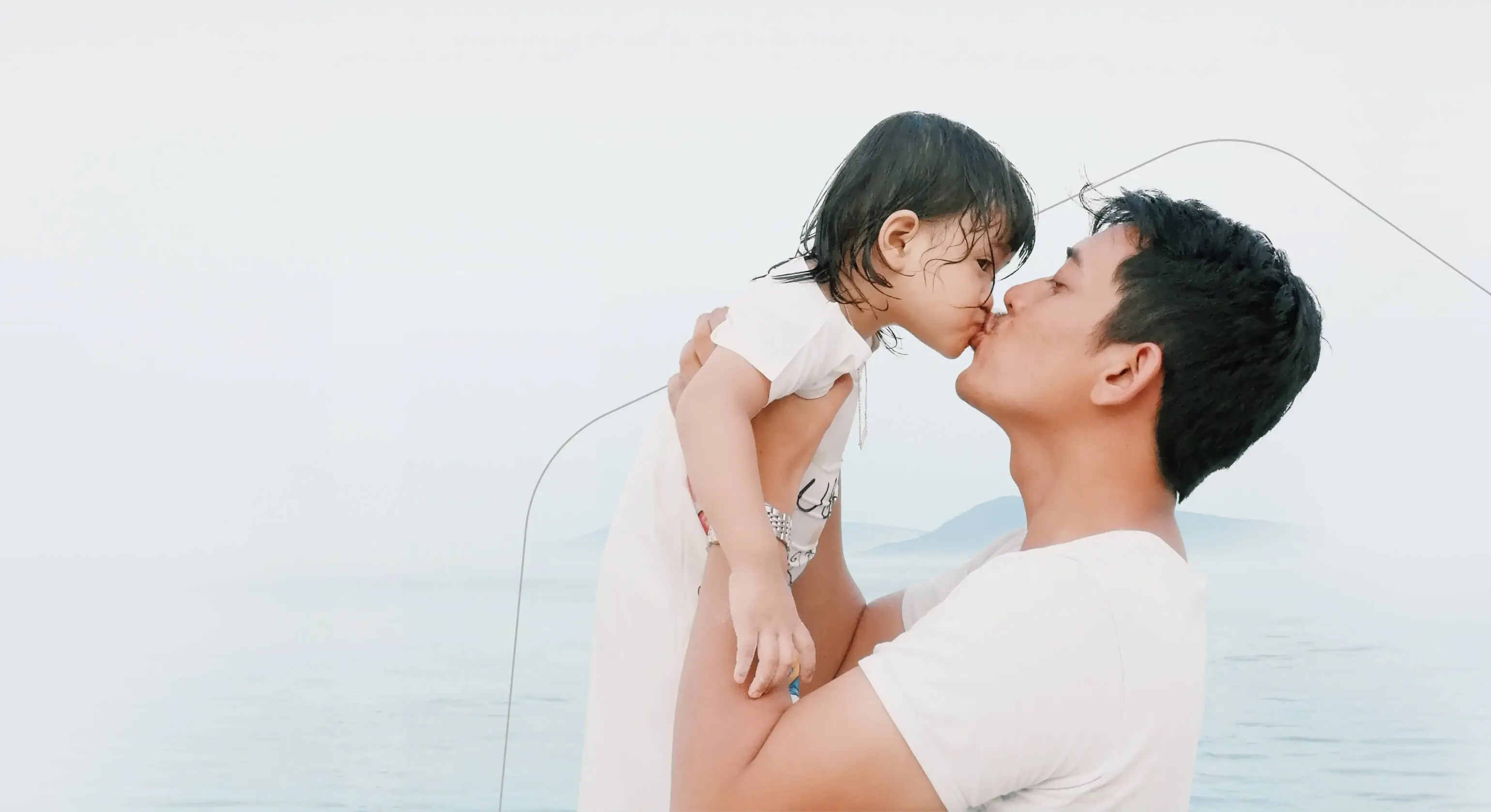 A father picks up his young child and give them a kiss.