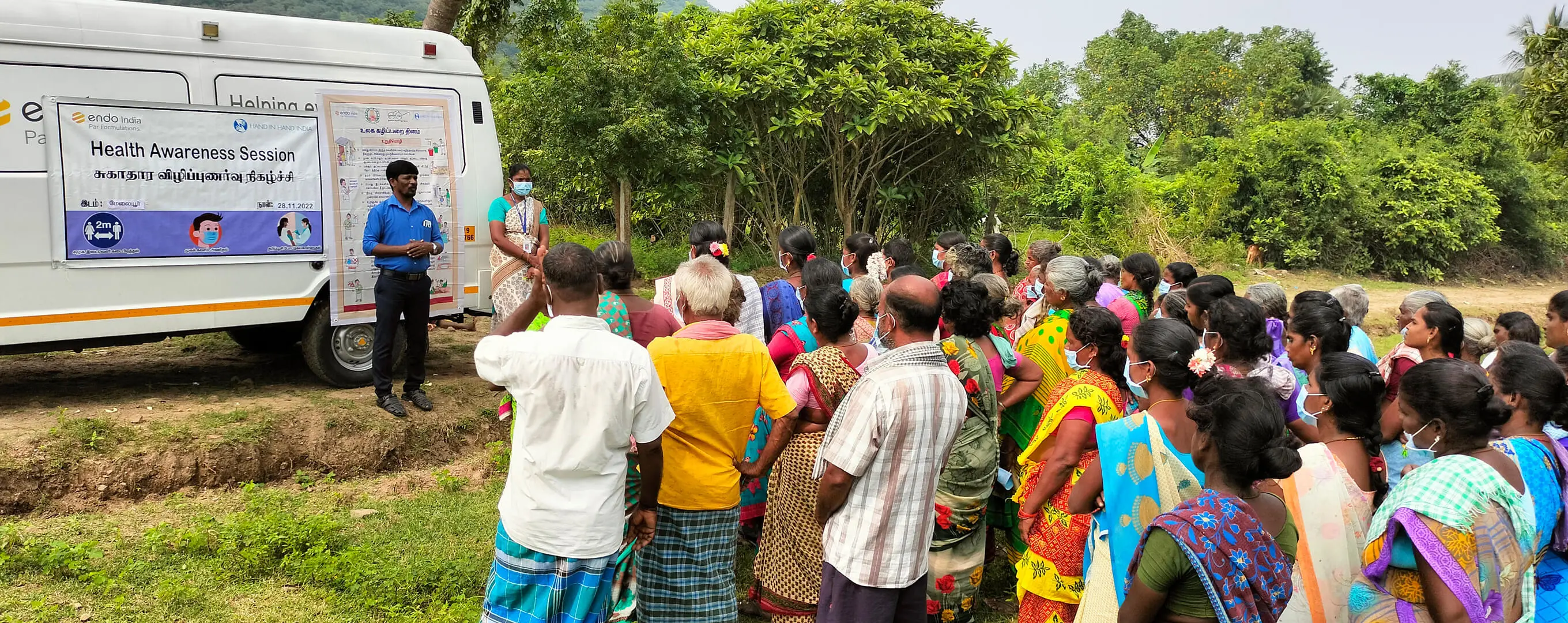 A group of patients in India gather outside a mobile health van.