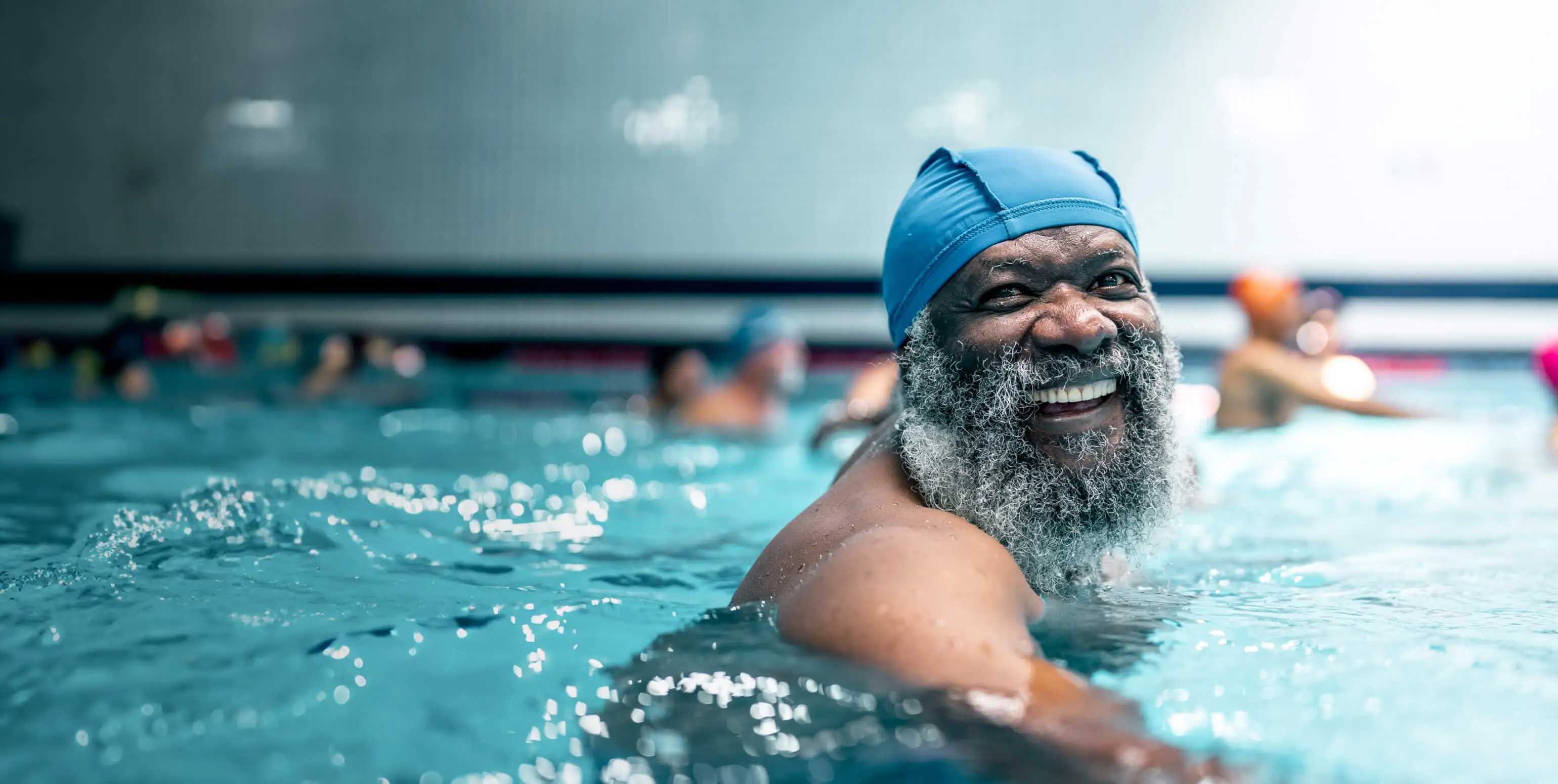 An older man smiles while swimming in a pool